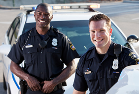Two police officers standing near parked car